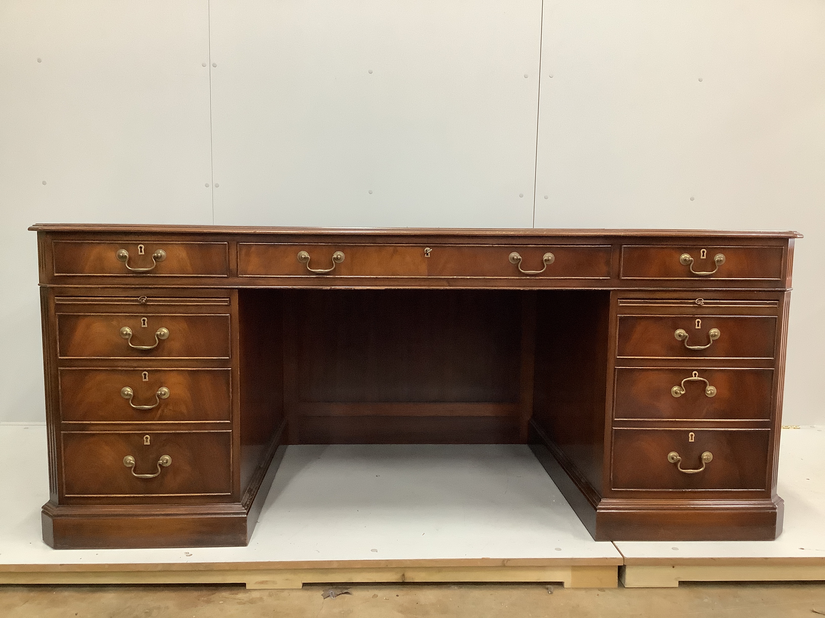 A reproduction George III style mahogany pedestal desk, width 180cm, depth 90cm, height 76cm together with a modern black leather and beech swivel desk chair